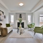 Large modern living room with hardwood flooring, bright open light and lime green accents.