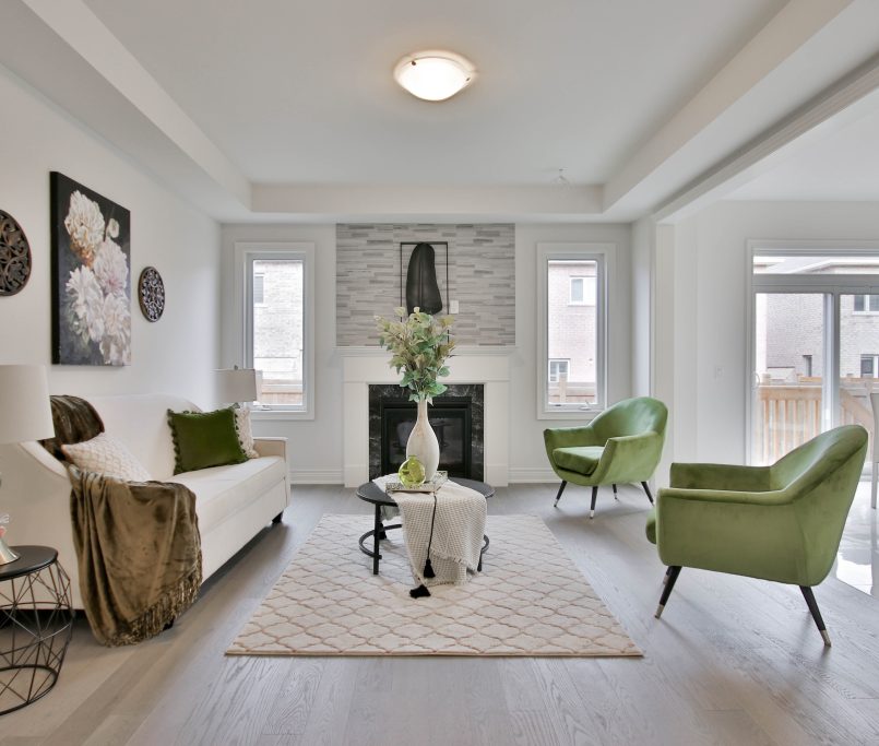 Large modern living room with hardwood flooring, bright open light and lime green accents.