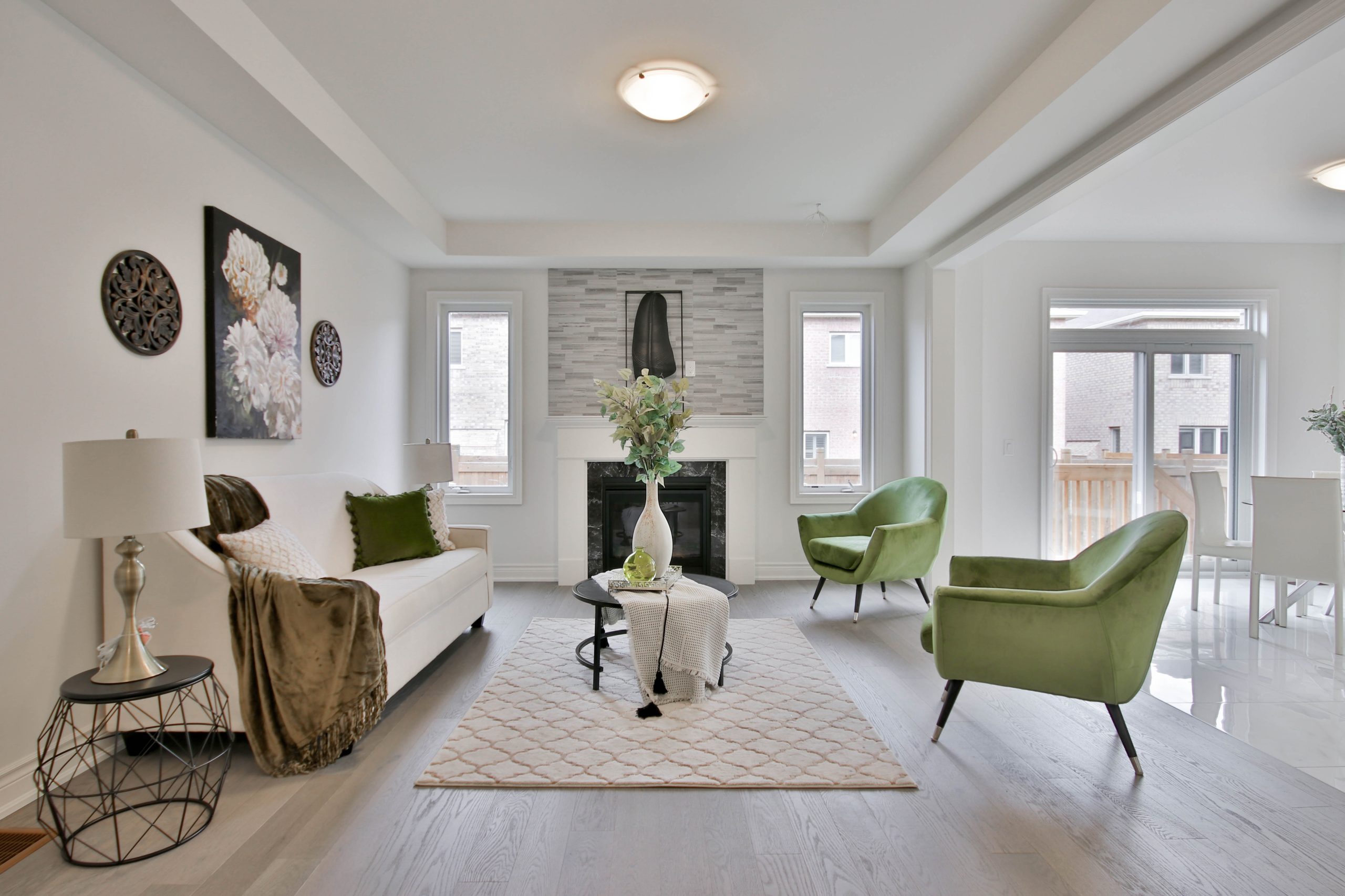 Large modern living room with hardwood flooring, bright open light and lime green accents.